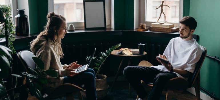 Man and woman with laptops, discussing something.
