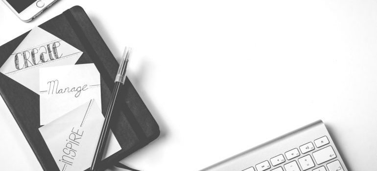 Notepad, laptop, and phone on white table