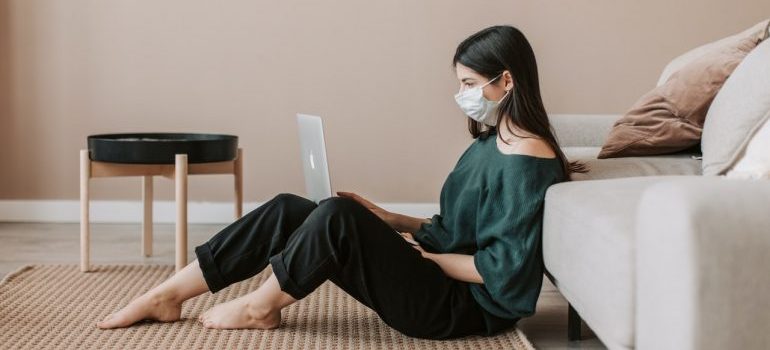 Woman sitting with her laptop, with a protective mask.