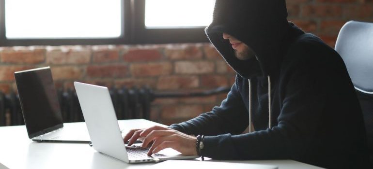 Person with a black hoodie, using a laptop