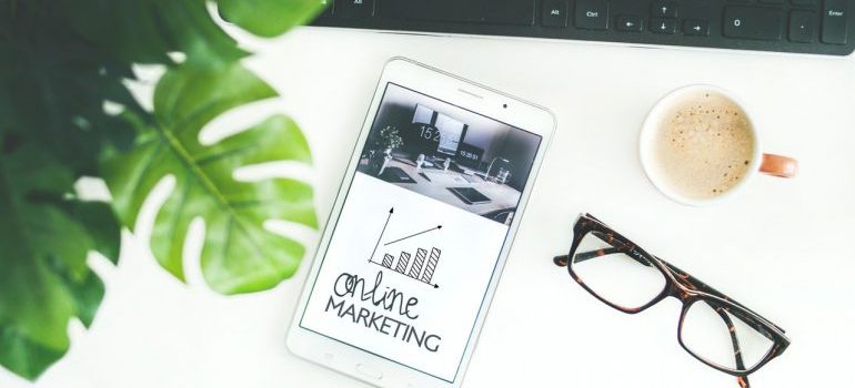 glasses, a cup of coffee and a tablet with word online marketing written on the screen