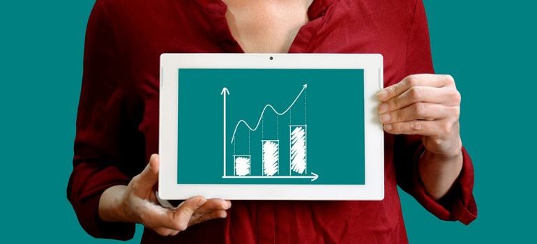 A woman holding a tablet that shows an upward graph.