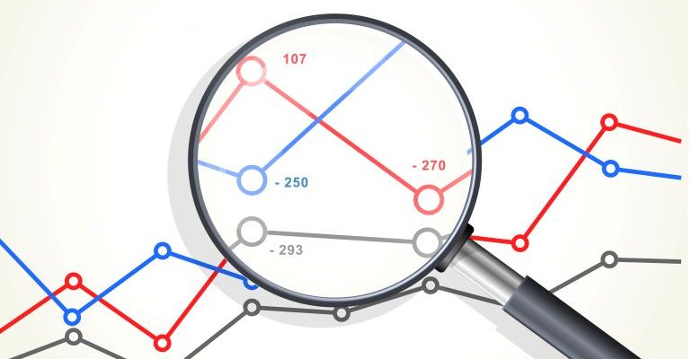 Magnifying glass looking at graphs and analytics chart.