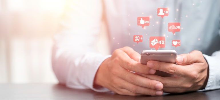 Person looking at phone with icons of likes, shares, etc.