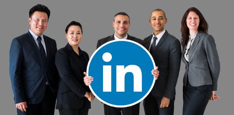 A team of business people, holding the LinkedIn logo sign.