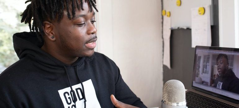 A man in a black shirt livestreaming on a laptop.