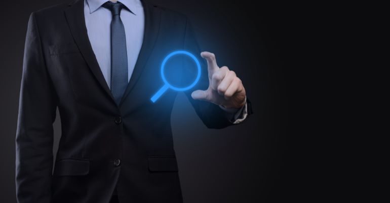 Businessman holding a blue magnifying glass icon.