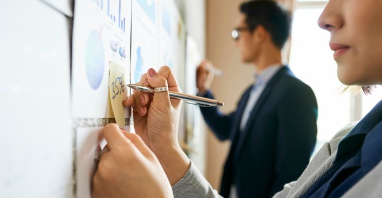 People in front of whiteboard, looking at graphs and metrics.