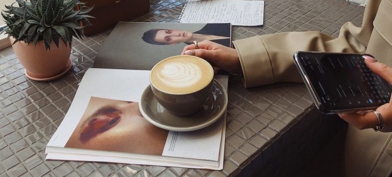 a girl drinking coffee and using her cell phone