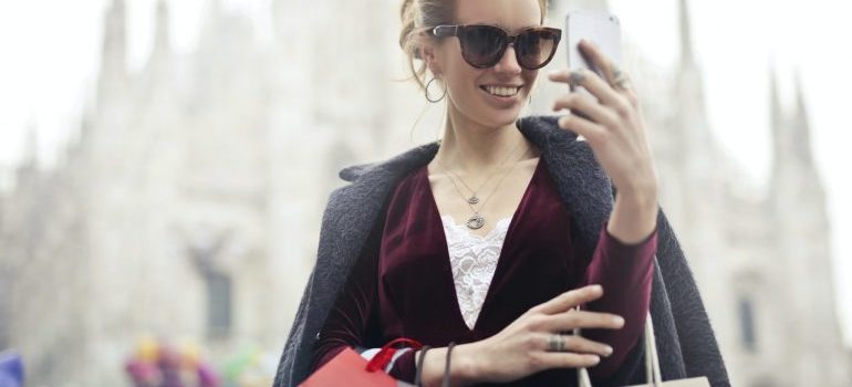 Woman looking at phone while carrying bags