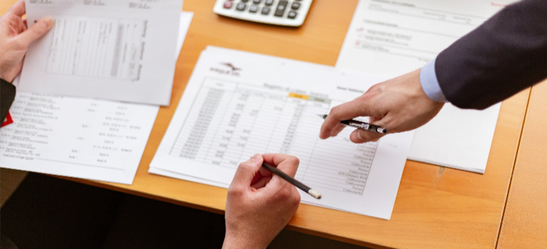 Two people on a table examining metrics on papers.
