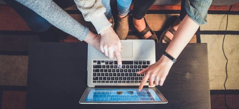 Three women sitting on a couch and looking at something on a laptop