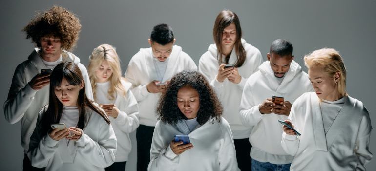 Group of people wearing white and looking at their phones