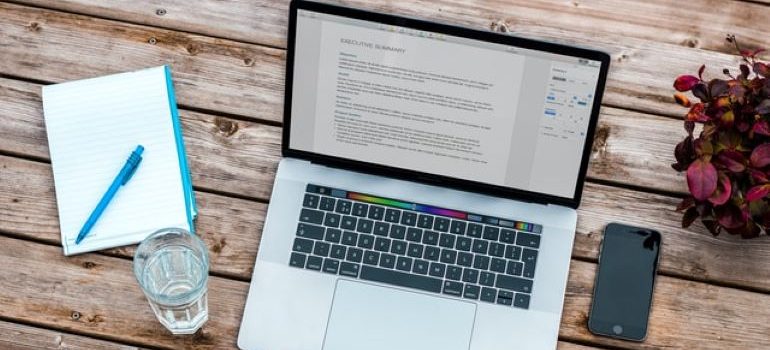 Glass of water and a notepad next to a laptop with a WordPress page opened on it