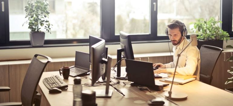 Customer service agent sitting at a desk and working on his laptop across and empty seat