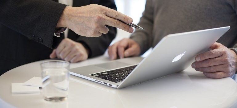 A professional working with a person on a laptop.