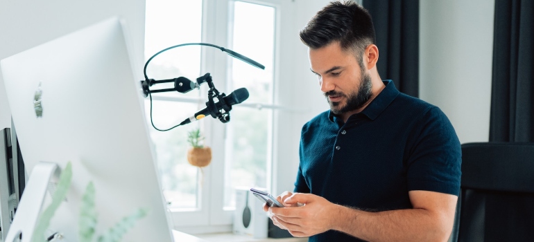 Man sitting in front of a computer and looking at his phone