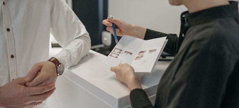 Sales person in a store explaining something to a customer and showing them flyer