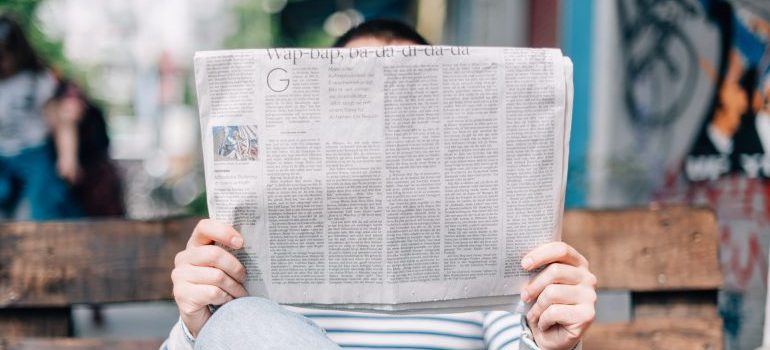 Person sitting on a bench and reading a newspaper as an example of traditional marketing channels