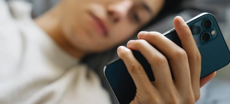 A young person in bed using a mobile phone.