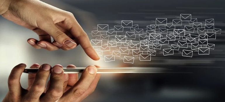An illustration of a person’s hands sending out emails through a mobile device.