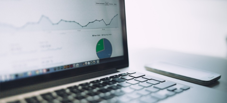 A gray laptop showing statistics and pie charts.