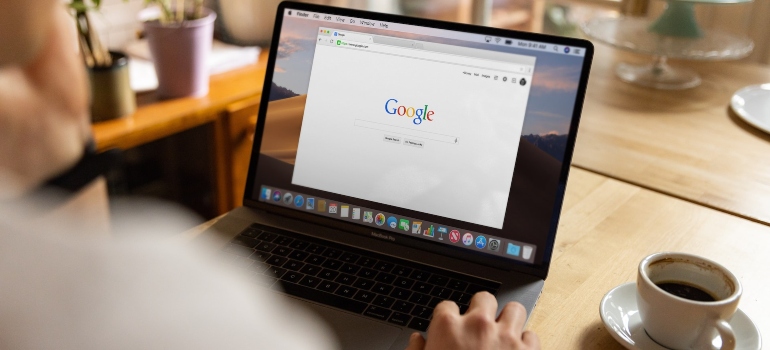 Photo of a laptop on a table next to a coffee mug with Google opened on it