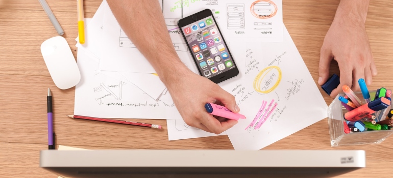 Person using a pink marker to write on a paper while doing a keyword research