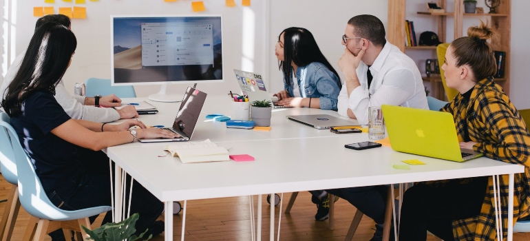 Five people sitting at a desk in an office and looking at a presentation