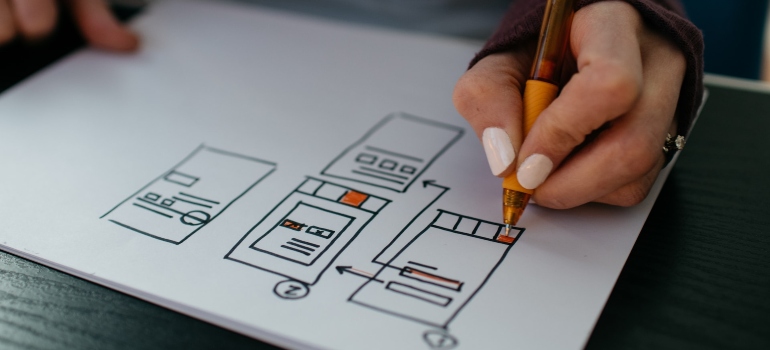 Person sketching a website design on a white paper