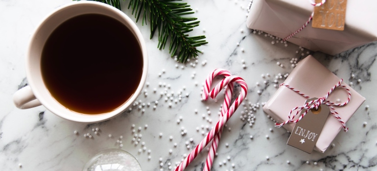 Photo of a coffee mug next to two sugar canes and two small wrapped Christmas presents