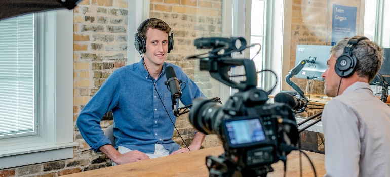 Cameraman recording a man wearing a blue shirt for a podcast