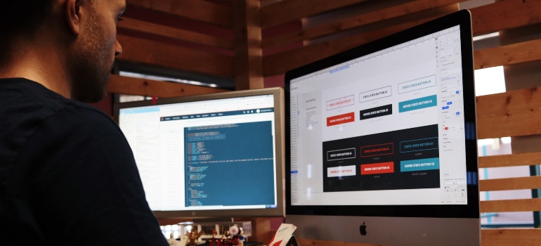 Person sitting at a desk and working while looking at two monitors