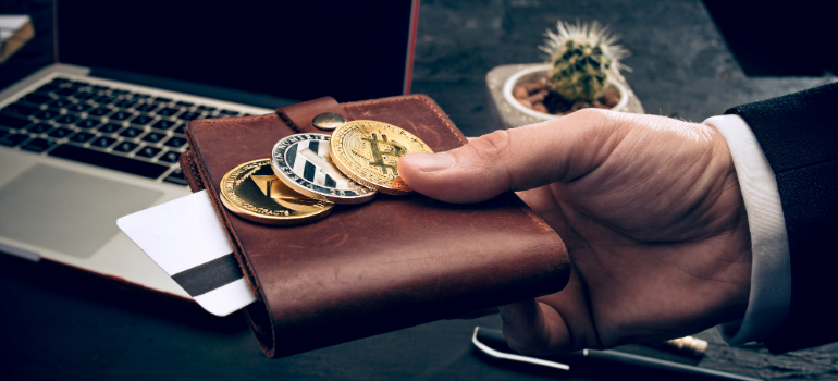 Person holding a wallet with three cryptocurrencies.