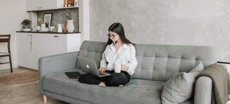Woman sitting on a couch in a living room and working on her laptop