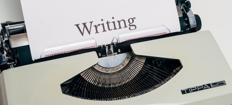 Typewriter with a paper that has Writing typed on it