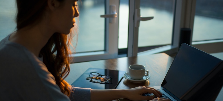 Woman sitting at a desk and writing a blog post on her laptop