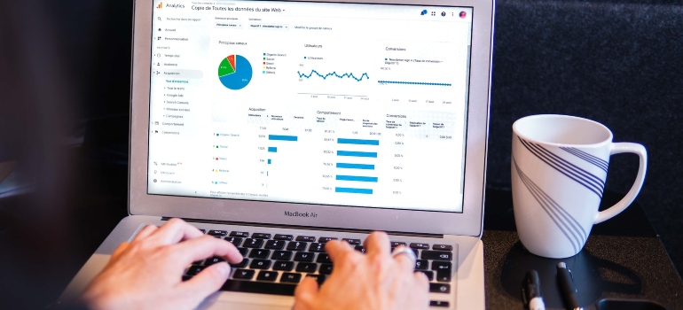 Person using Google Analytics on a laptop that's next to a coffee mug