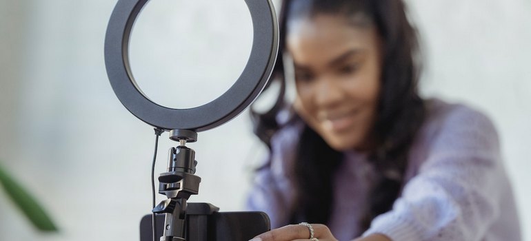 a woman adjusting a phone behind a ring light while creating organic social media vs paid content