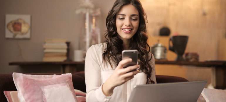 Woman sitting at a desk and looking at her phone while smiling