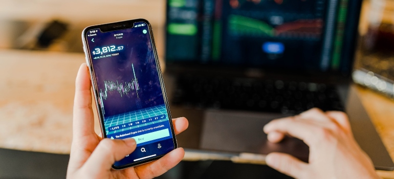 Person checking their bank account balance on their mobile phone and on their laptop