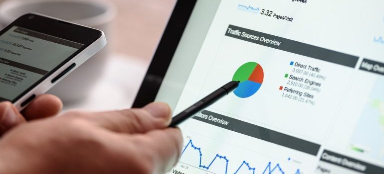 A person comparing data shown on the laptop screen.