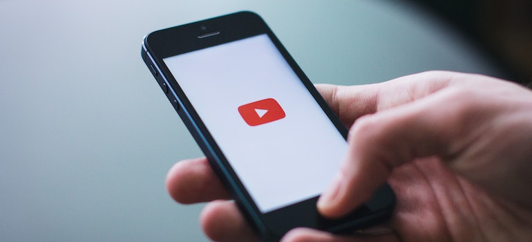 A person holding a phone with a YouTube sign on the screen
