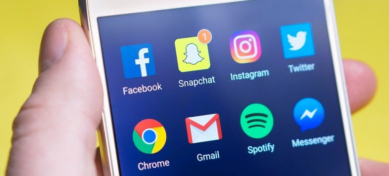 A person holding a phone that has social media apps installed
