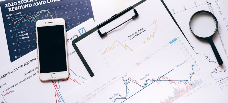 Smartphone and a magnifying glass on a pile of papers