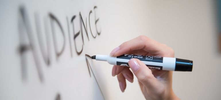 Person writing the word "audience" on a white board