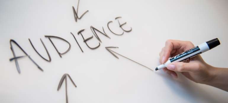 Person writing the word "audience" on a white board