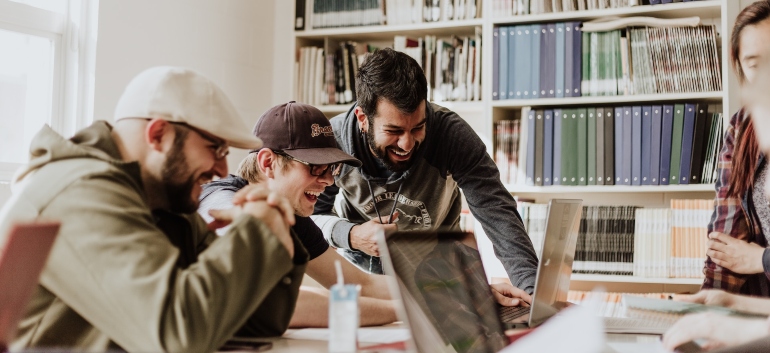Group of people in an office sitting in front of a laptop