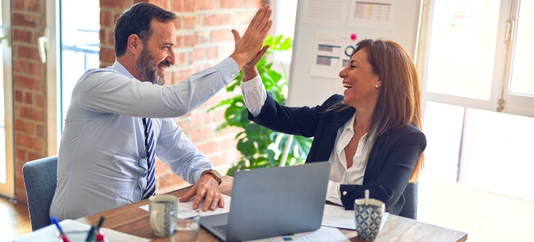 Two people high fiving after a successful meeting about how web design affects SEO