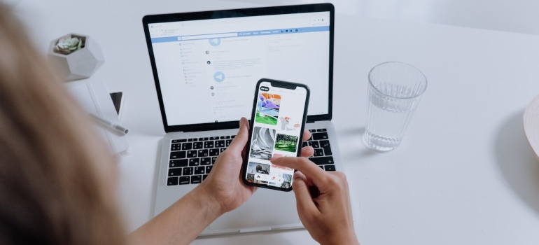 Person using social media on their phone in front of their laptop